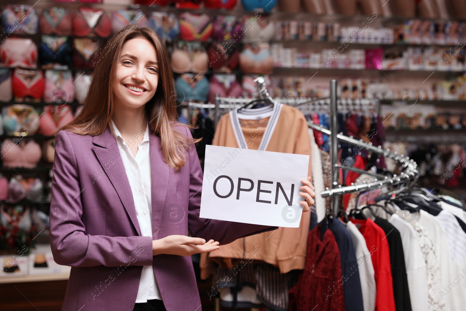 Photo of Young business owner holding OPEN sign in boutique