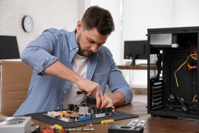 Male technician repairing motherboard at table indoors