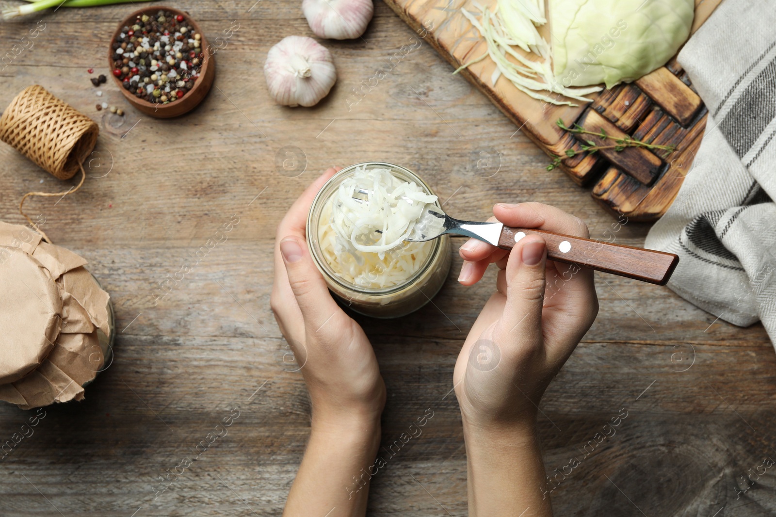 Photo of Woman eating fermented cabbage at wooden table, top view