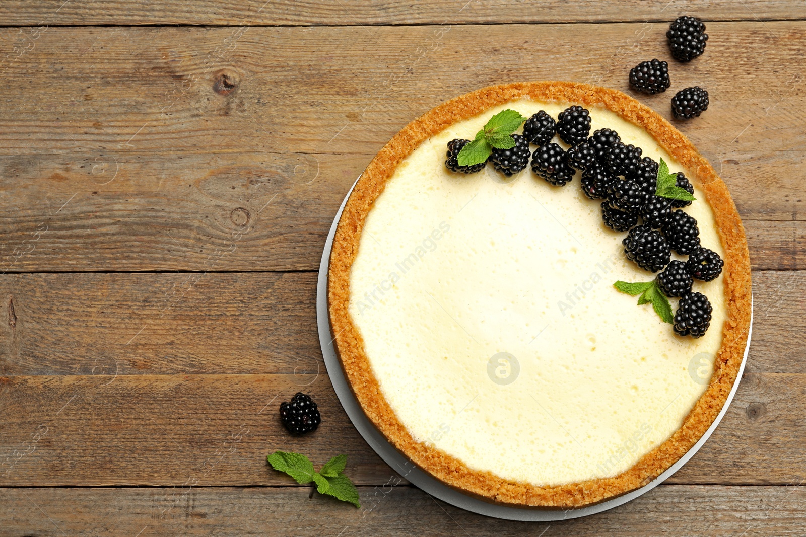 Photo of Delicious cheesecake decorated with blackberries on wooden table, flat lay. Space for text