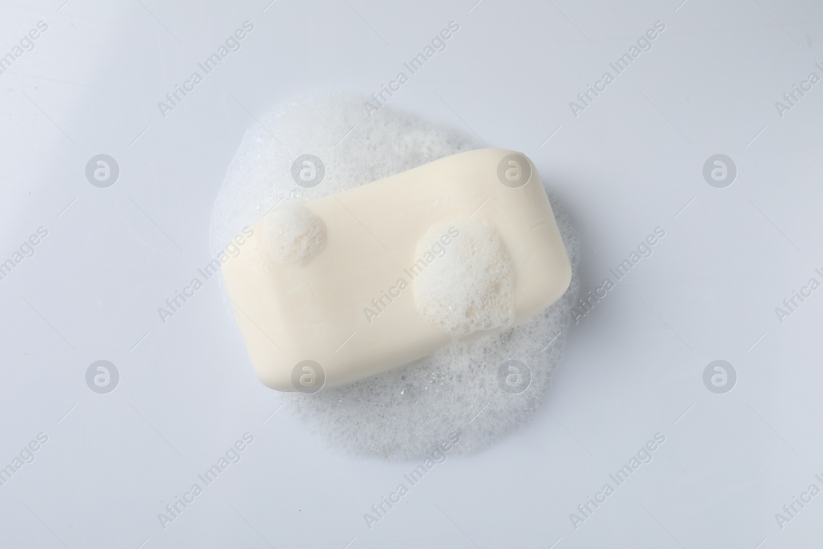 Photo of Soap with fluffy foam on white background, top view