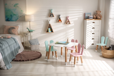 Small table and chairs with bunny ears in children's room interior