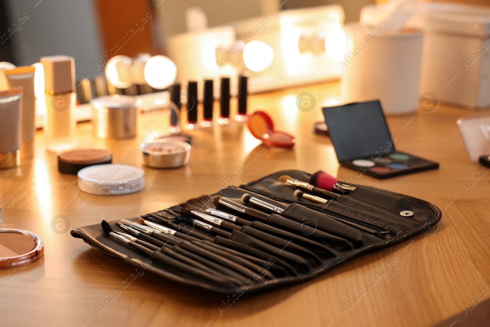 Photo of Set of makeup brushes and cosmetics on wooden table