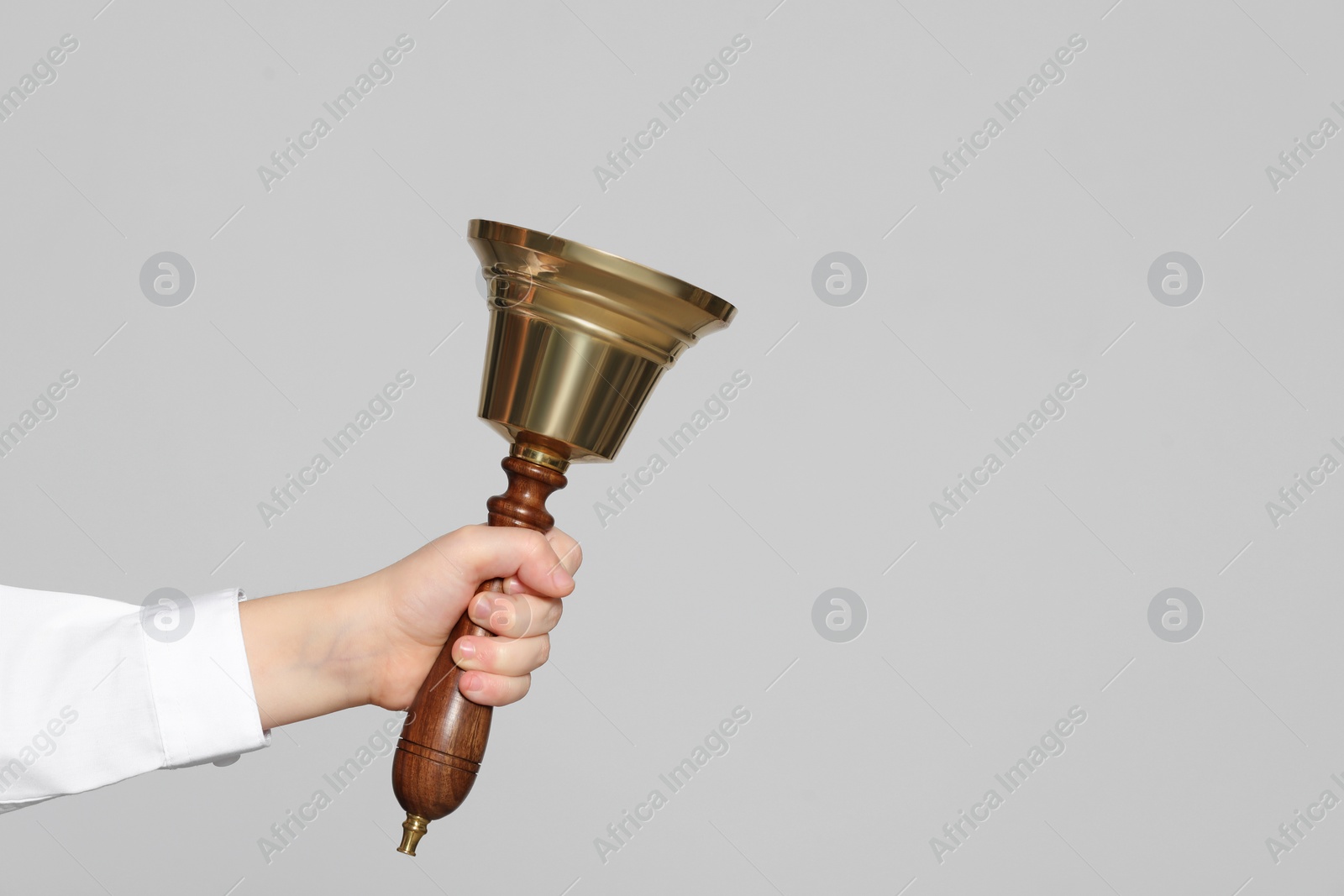 Photo of Pupil with school bell on light grey background, closeup. Space for text