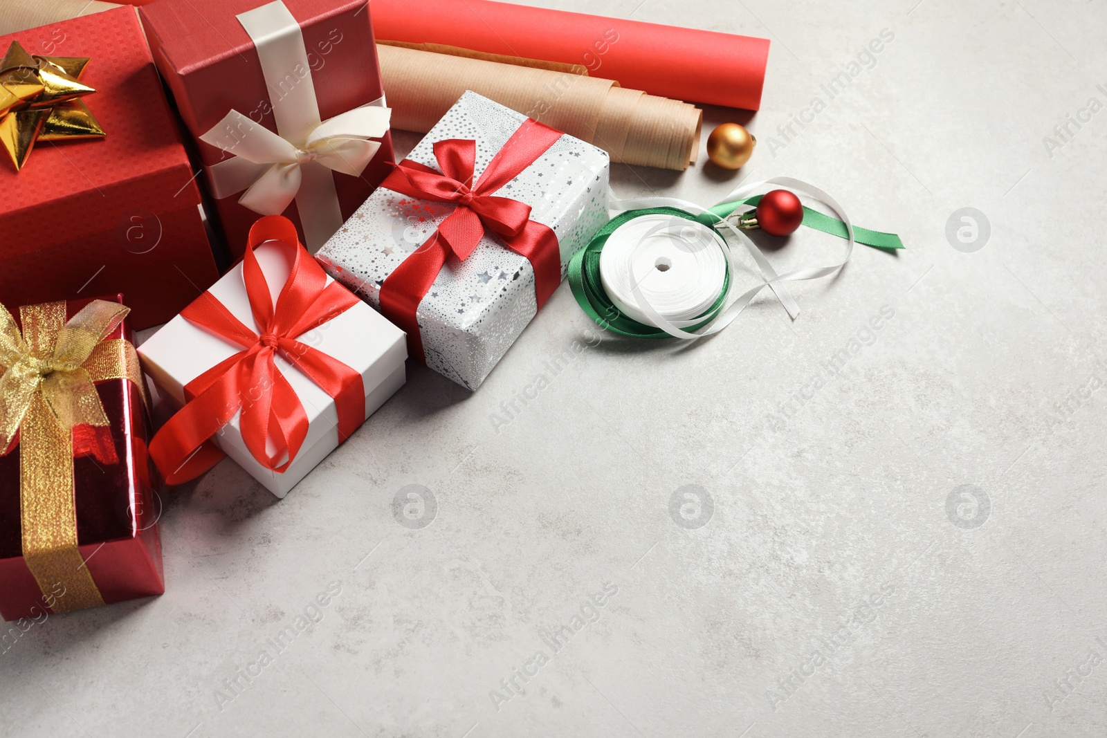 Photo of Beautiful Christmas gift boxes wrapped in paper and decorated with bows on light table, space for text