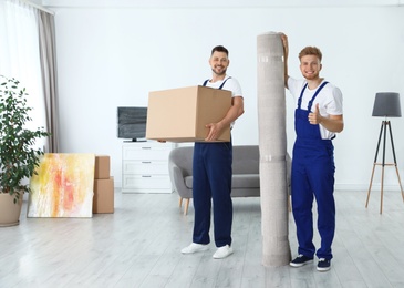 Photo of Moving service employees with box and carpet in room