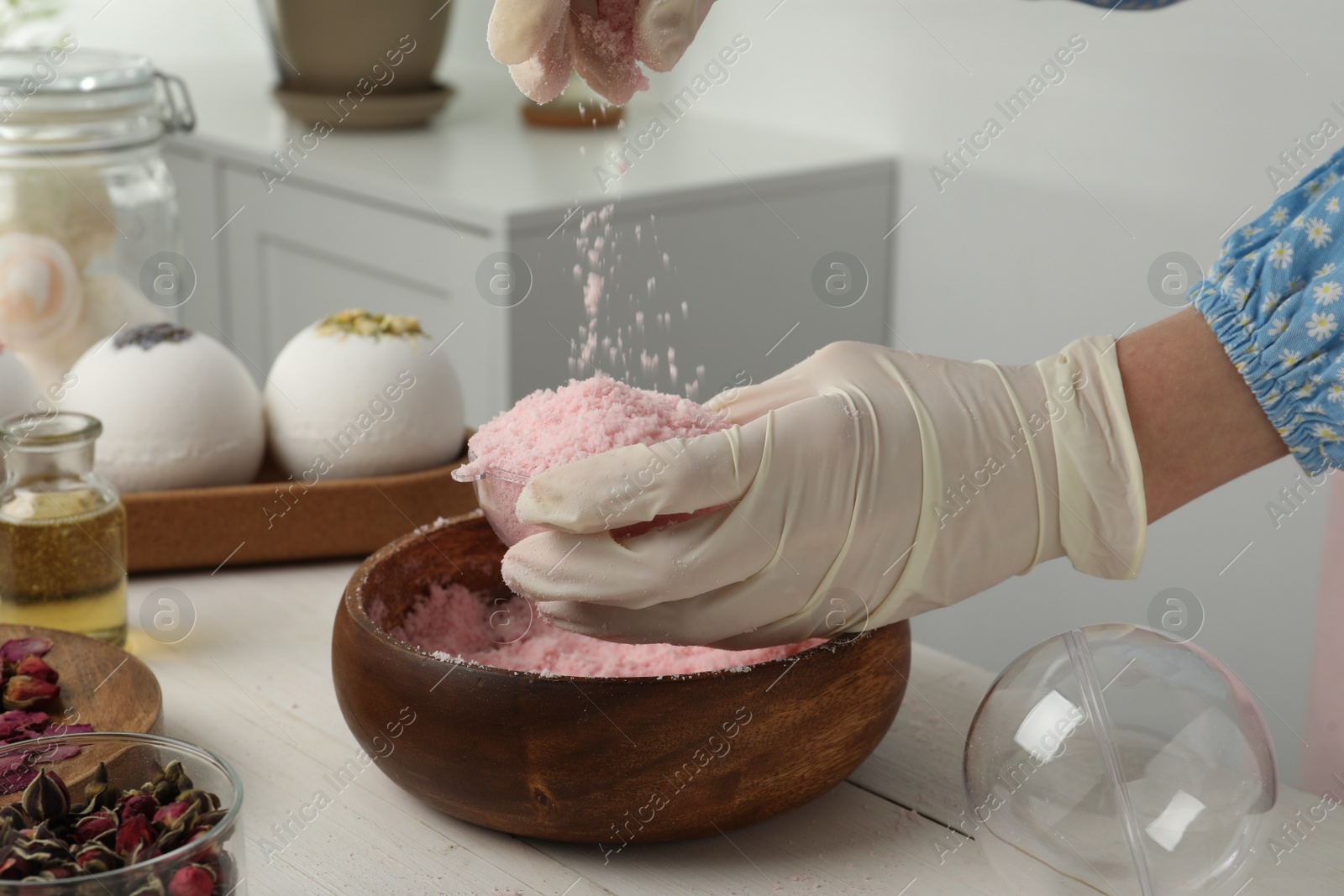 Photo of Woman in gloves making bath bomb at white table, closeup