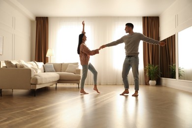 Happy couple dancing barefoot in living room. Floor heating system