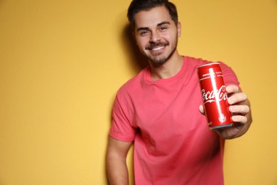 MYKOLAIV, UKRAINE - NOVEMBER 28, 2018: Young man with Coca-Cola can on color background, space for text