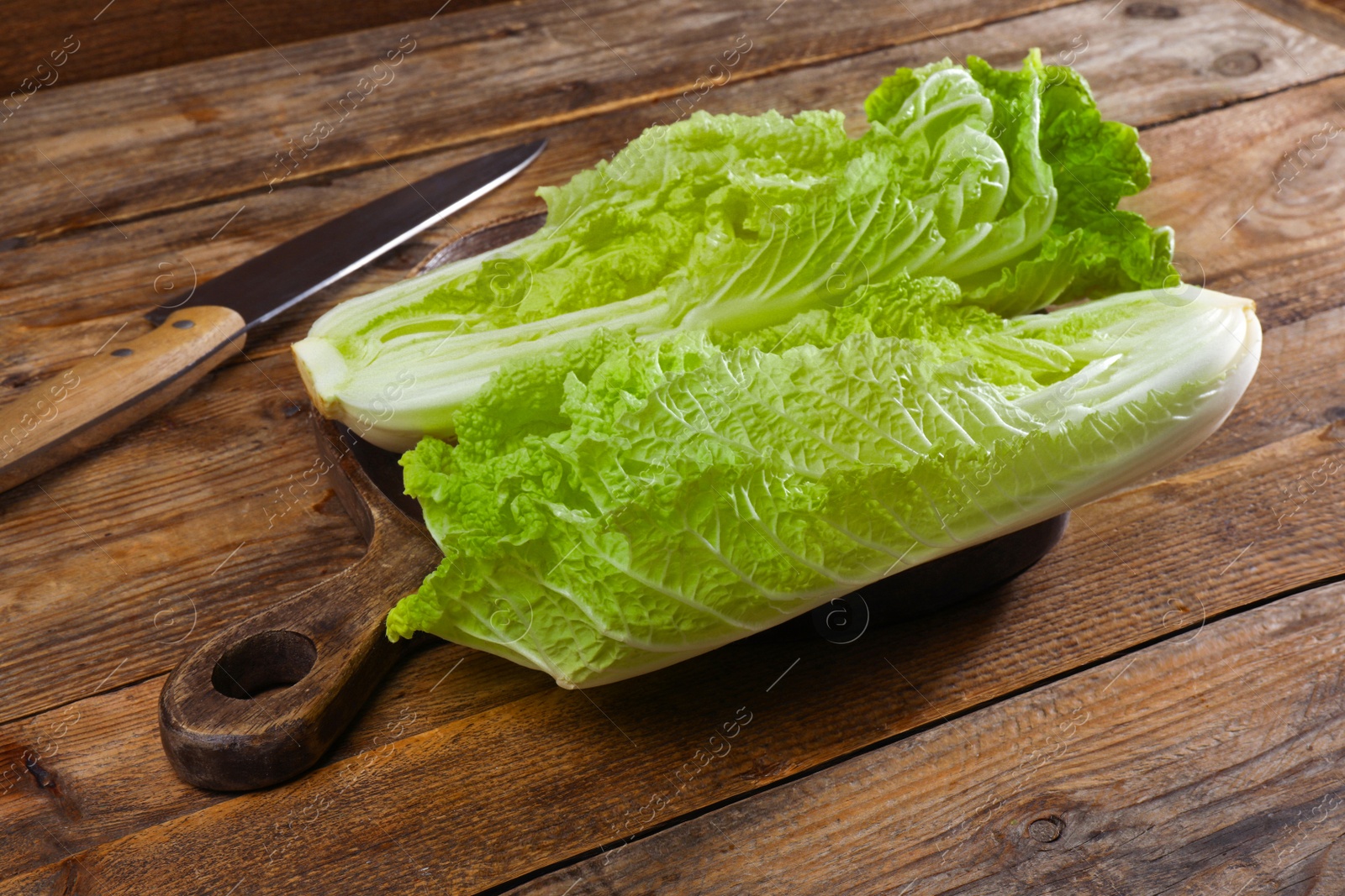 Photo of Halves of fresh ripe Chinese cabbage on wooden table