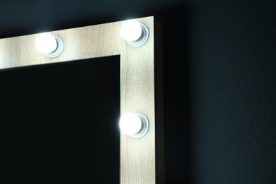 Photo of Mirror with light bulbs on color wall, closeup view with space for text. Dressing room