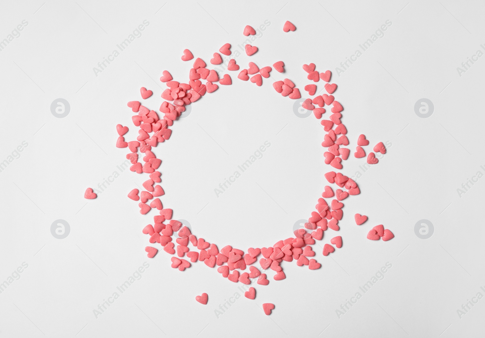 Photo of Round frame made of pink heart shaped sprinkles on white background, flat lay. Space for text