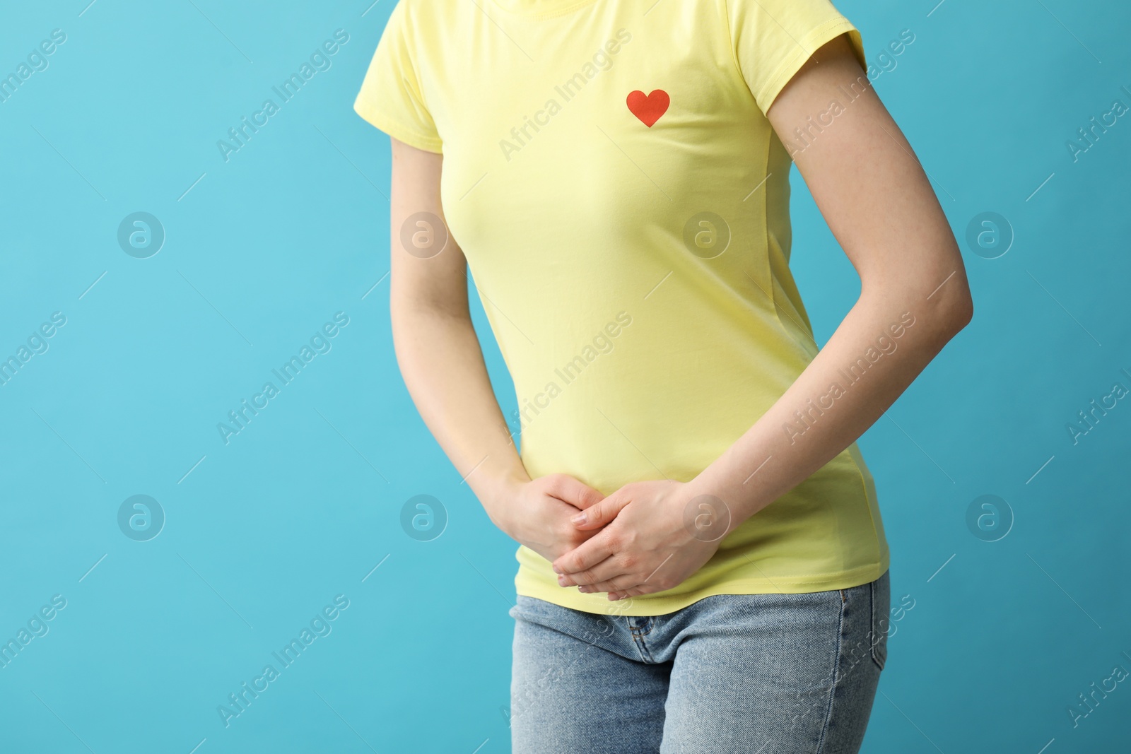 Photo of Woman suffering from cystitis on light blue background, closeup. Space for text