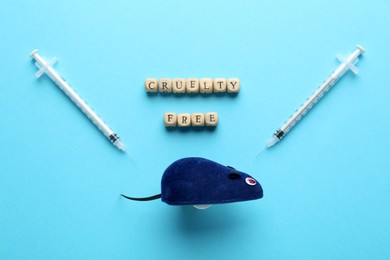Photo of Wooden cubes with text Cruelty Free, mouse toy and syringes on turquoise background, flat lay. Stop animal tests
