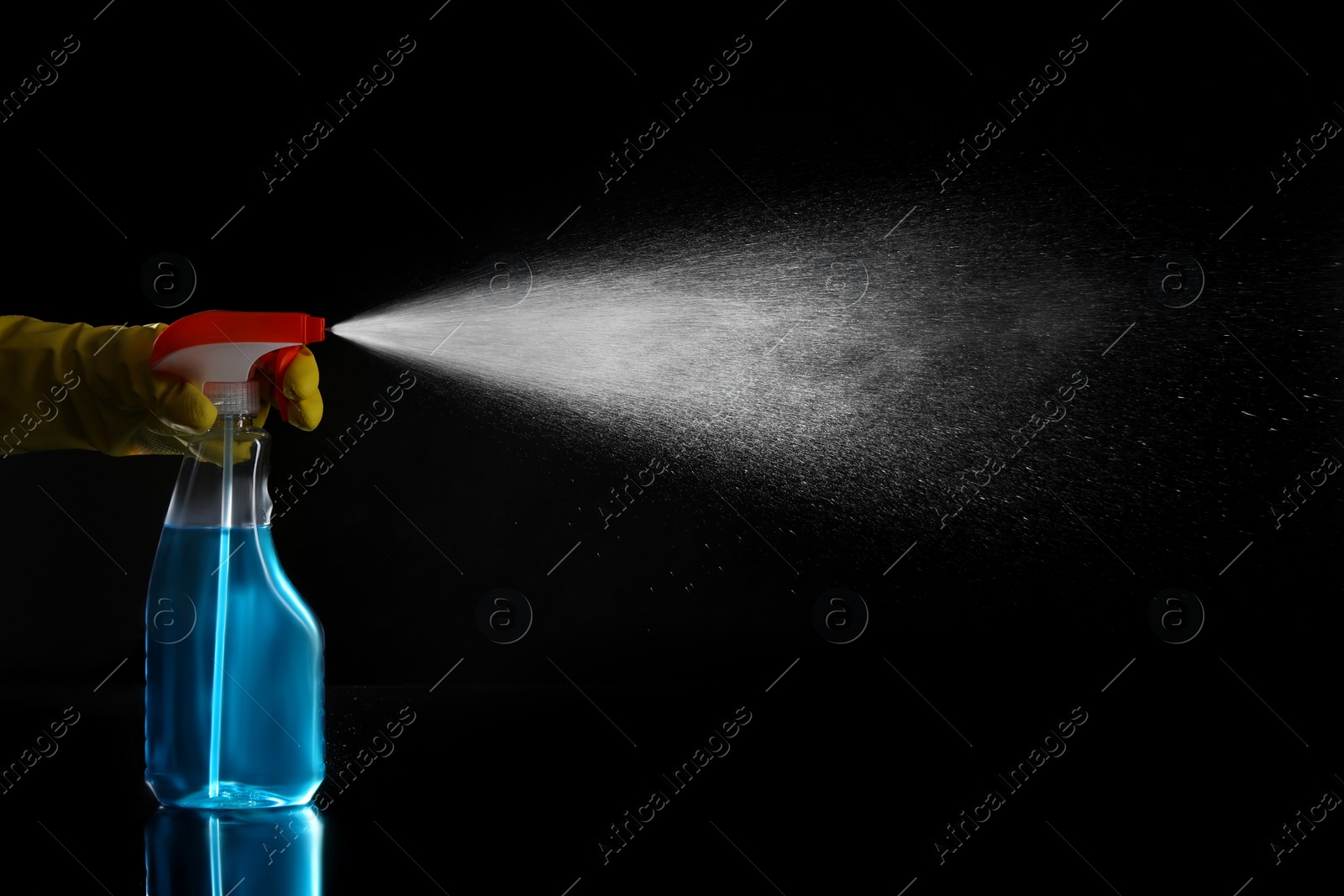 Photo of Woman spraying liquid from bottle on black background, closeup