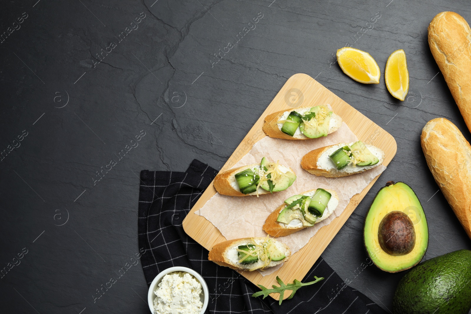 Photo of Flat lay composition with avocado sandwiches on dark grey table