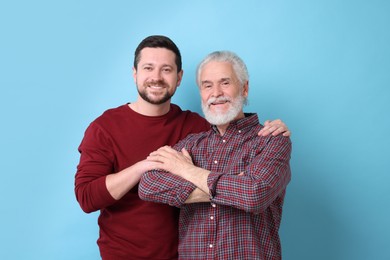 Happy son and his dad on light blue background