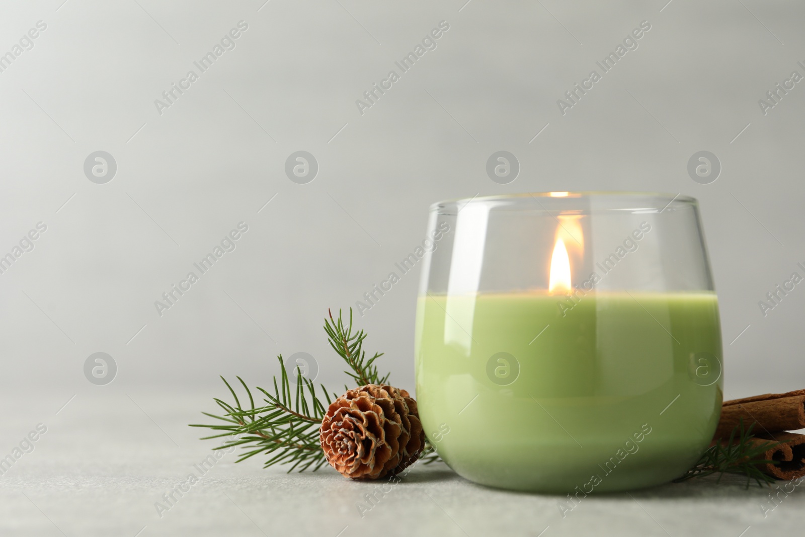 Photo of Composition with burning candle and pinecone on light grey table, space for text