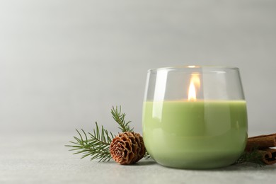 Photo of Composition with burning candle and pinecone on light grey table, space for text
