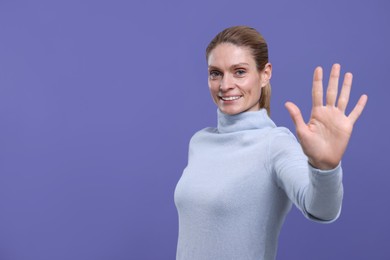 Photo of Woman giving high five on purple background, space for text