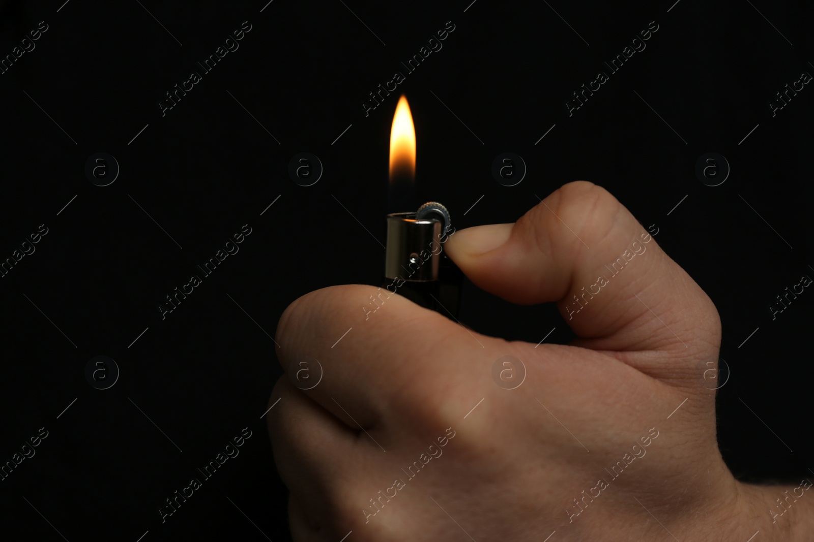 Photo of Man holding lighter on black background, closeup