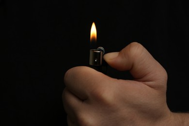 Photo of Man holding lighter on black background, closeup