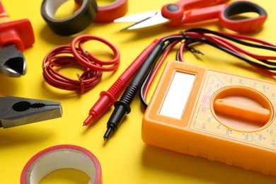 Photo of Set of electrician's tools and accessories on yellow background, closeup