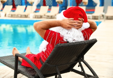 Authentic Santa Claus on lounge chair near pool at resort