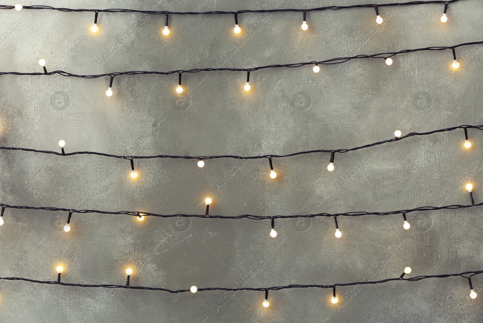 Photo of Christmas lights hanging on grey stone wall