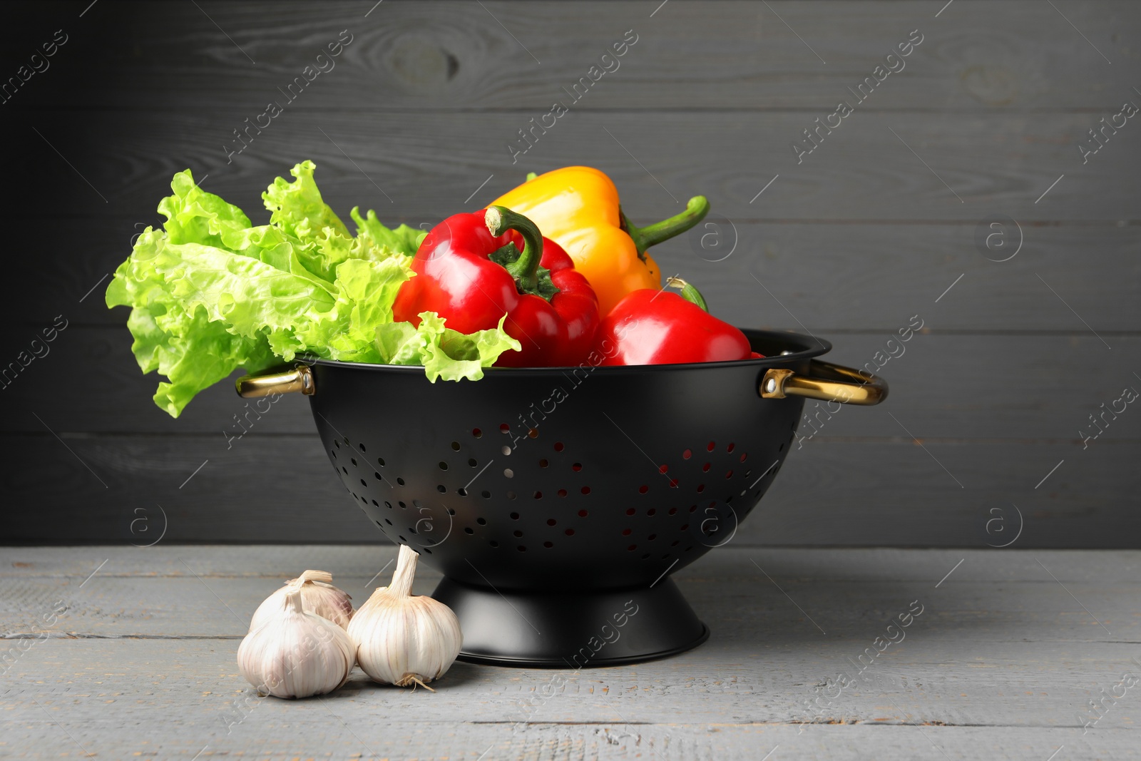 Photo of Black colander and different vegetables on rustic wooden table