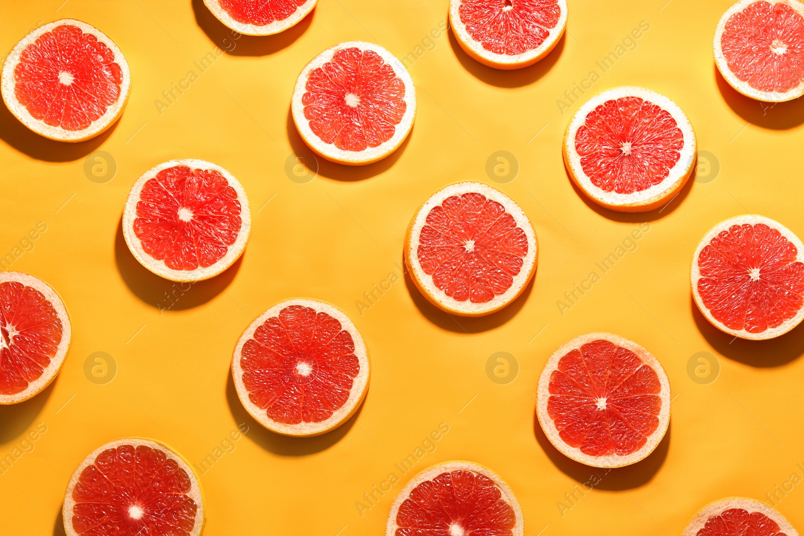 Photo of Flat lay composition with tasty ripe grapefruit slices on orange background