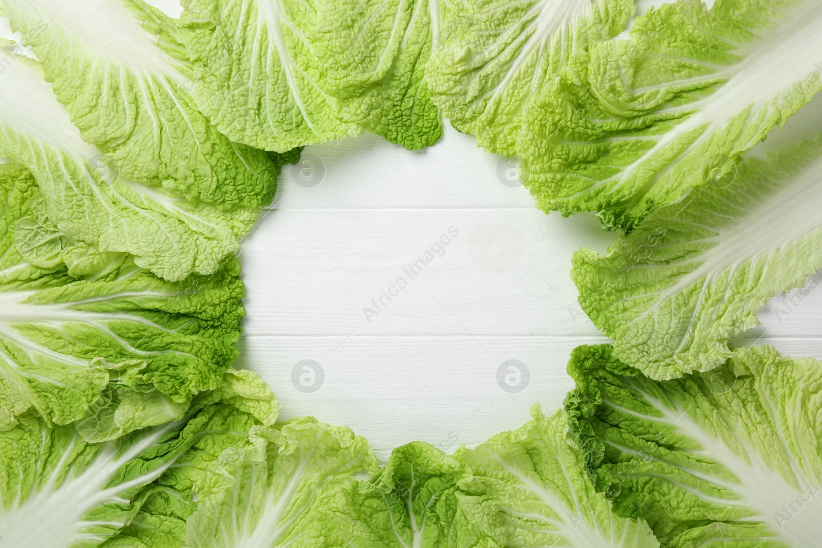 Photo of Frame with fresh ripe leaves of Chinese cabbage on white wooden table, flat lay. Space for text