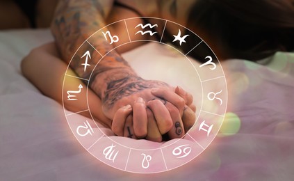 Image of Sexual compatibility. Zodiac wheel and passionate couple having sex on bed, closeup of hands