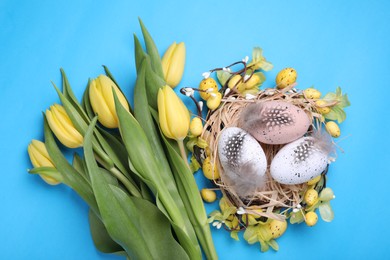 Flat lay composition with beautiful flowers and eggs on light blue background. Easter celebration