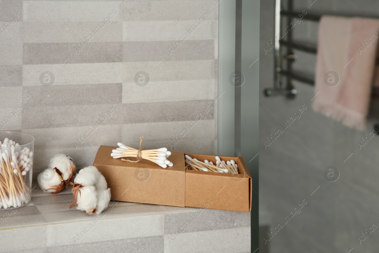 Photo of Cotton swabs and flowers on tiled surface in bathroom