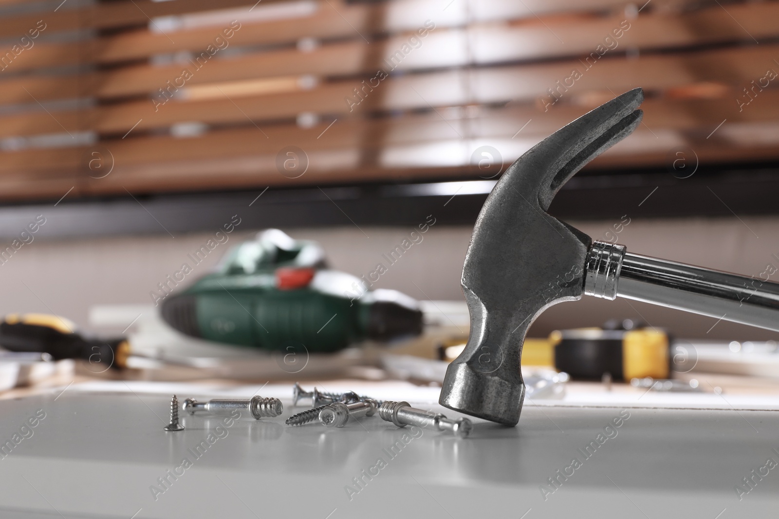 Photo of Set of different fasteners and hammer on white table indoors. Furniture assembly