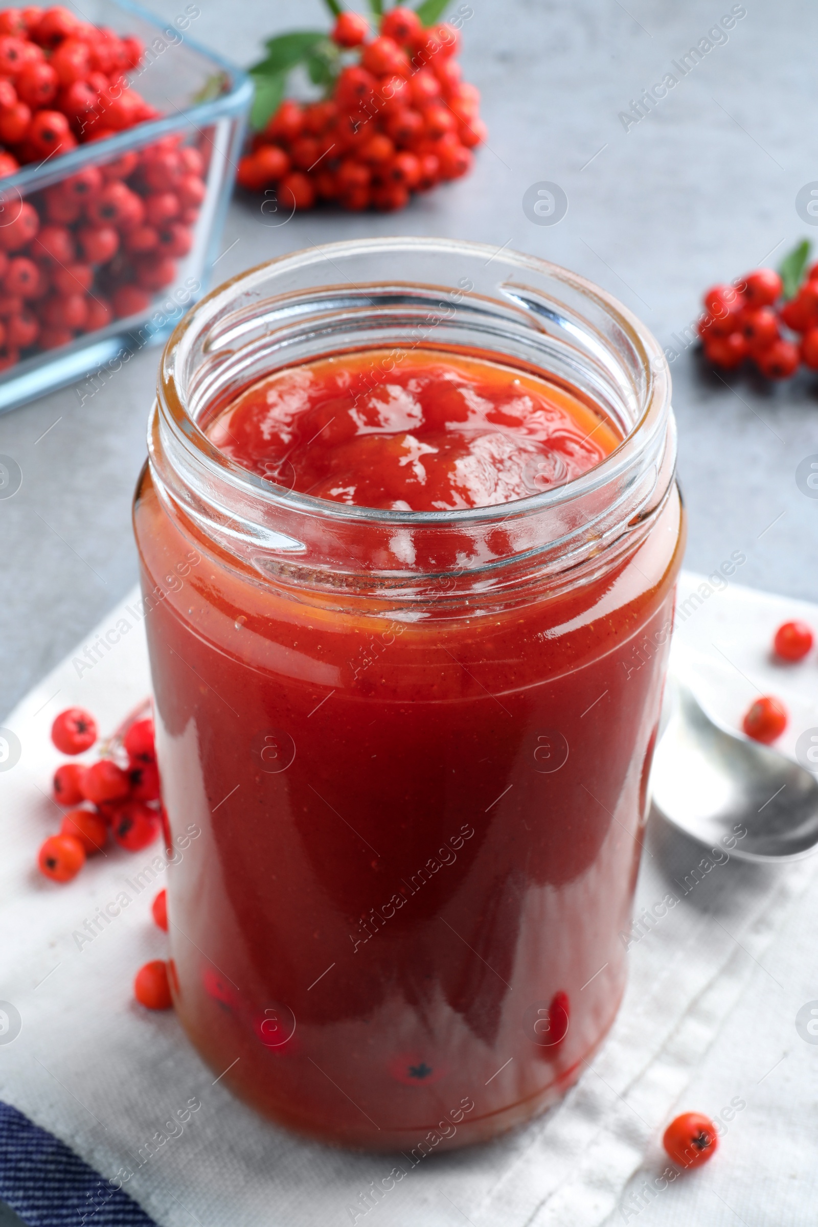 Photo of Delicious rowan jam in glass jar on grey table