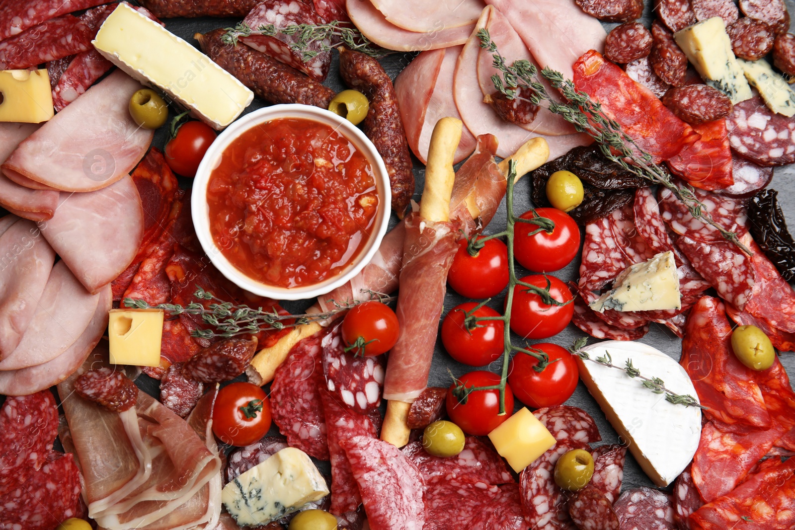 Photo of Tasty ham with other delicacies on black table, flat lay