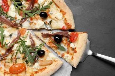 Tasty pizza with anchovies, arugula and olives on black table, top view