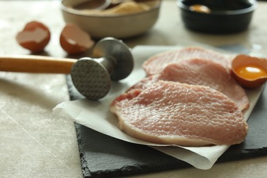 Photo of Cooking schnitzel. Raw pork chops, meat mallet and ingredients on grey table, closeup