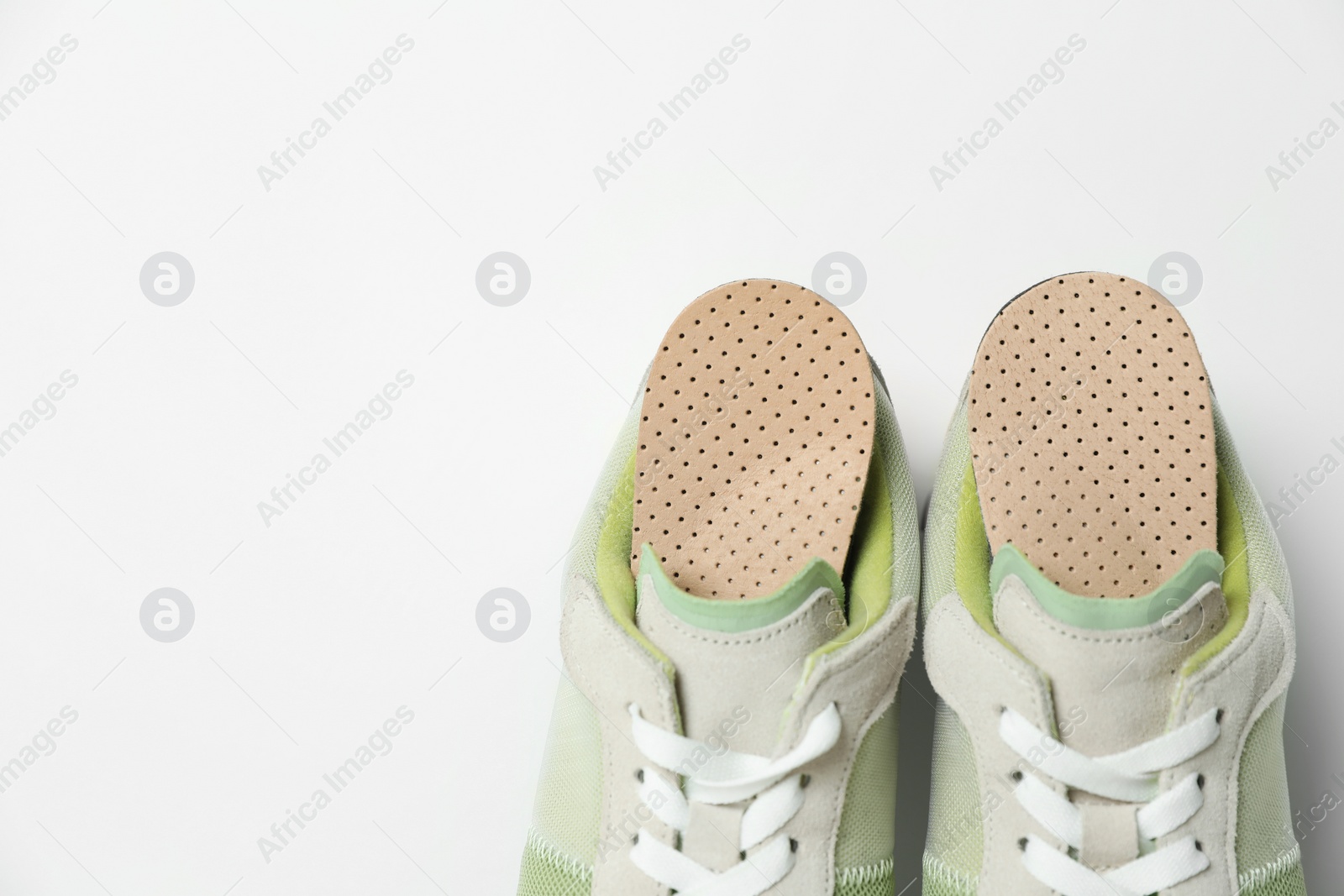 Photo of Orthopedic insoles in shoes on white background, closeup. Space for text