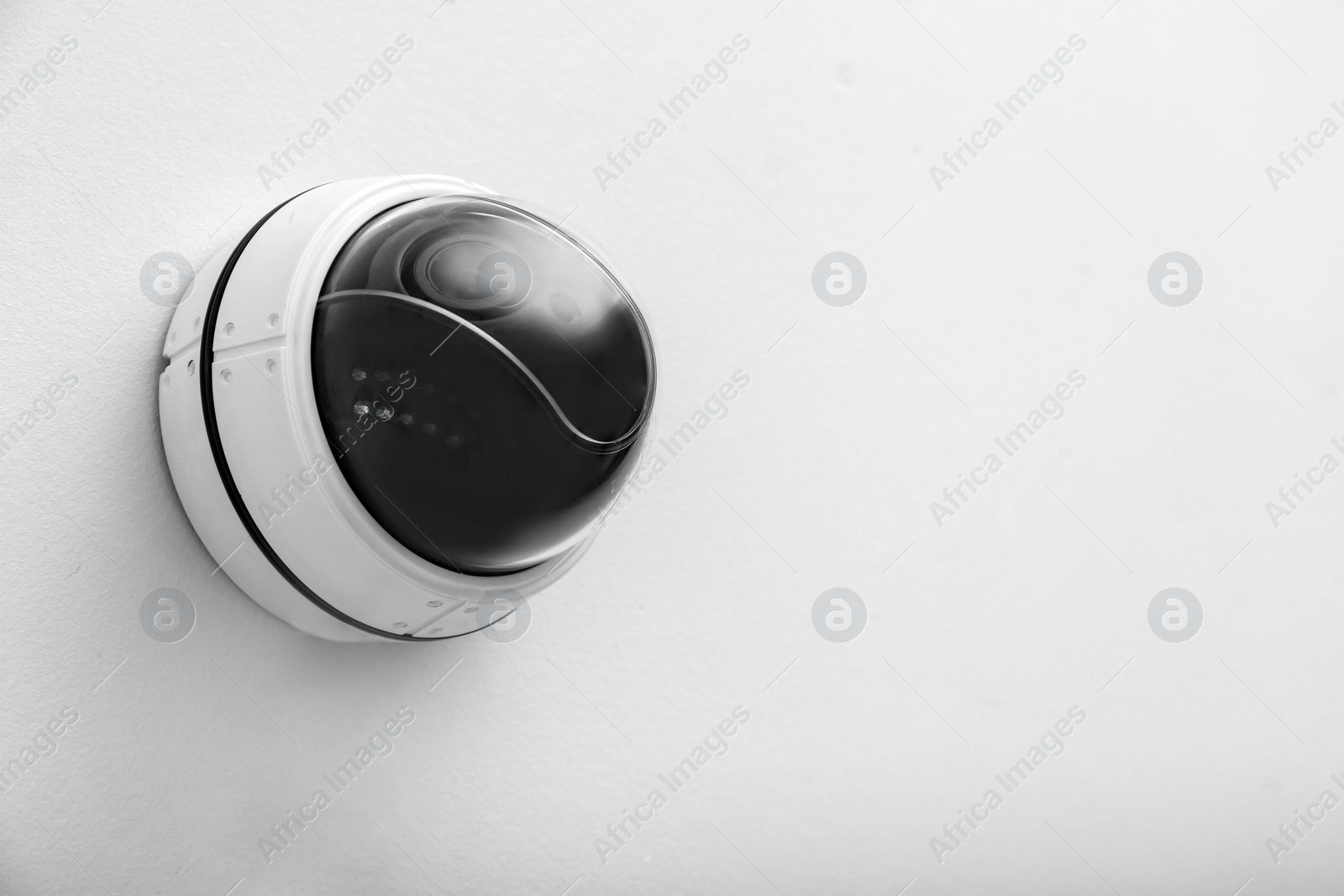 Photo of Modern CCTV security camera on white wall. Space for text