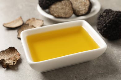 Photo of Bowl of truffle oil on light grey table, closeup