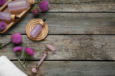 Photo of Flat lay composition with essential oil and flowers on wooden background. Space for text