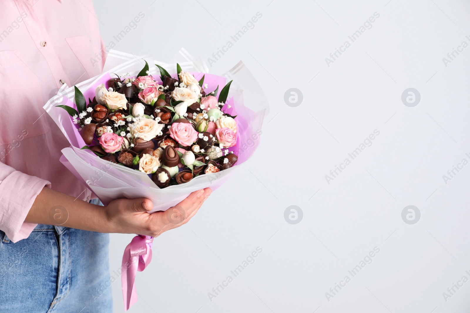 Photo of Woman with beautiful food bouquet on light grey background, closeup. Space for text