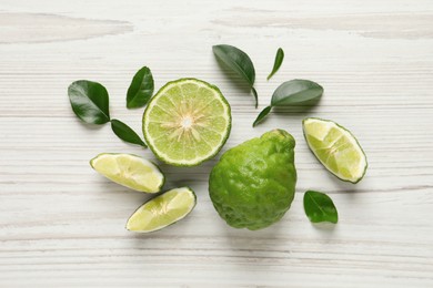 Fresh ripe bergamot fruits with green leaves on white wooden table, flat lay