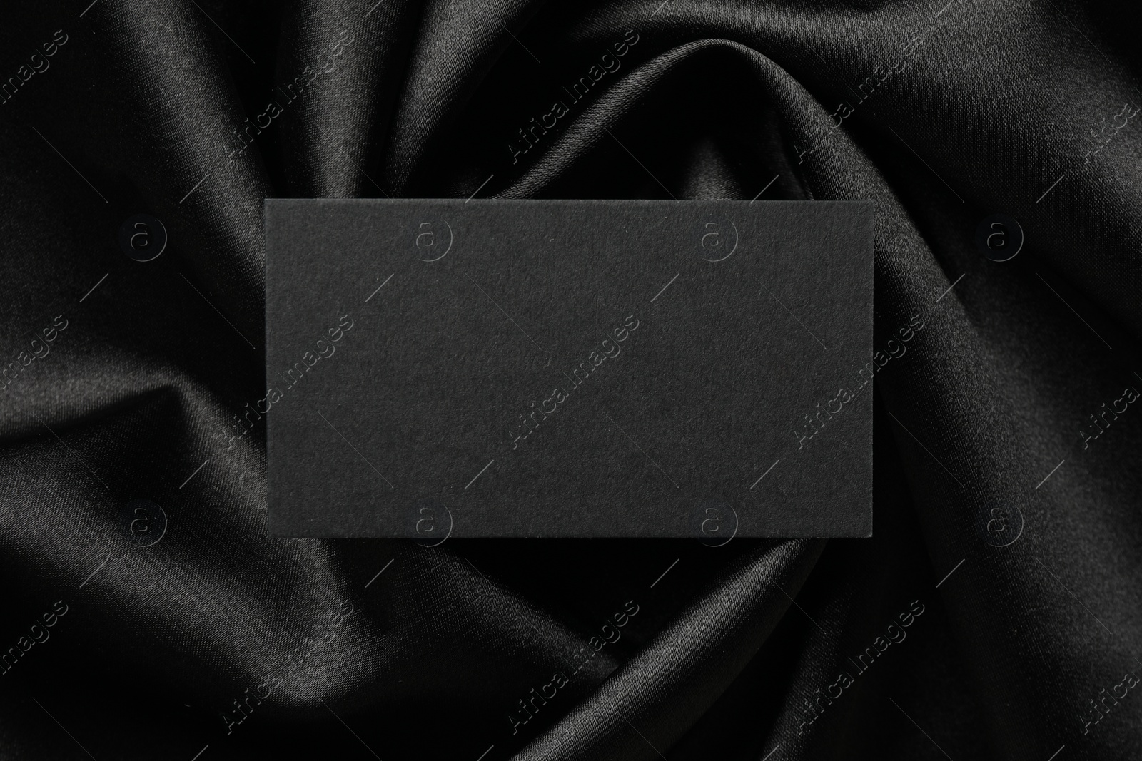 Photo of Blank business card on black fabric, top view. Mockup for design