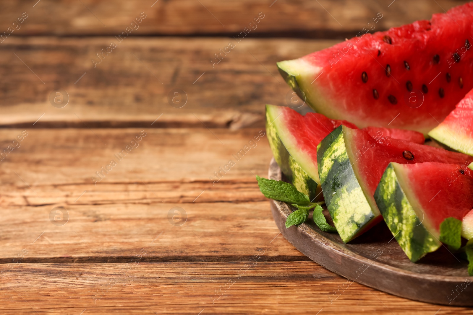 Photo of Slices of delicious ripe watermelon on wooden table, space for text