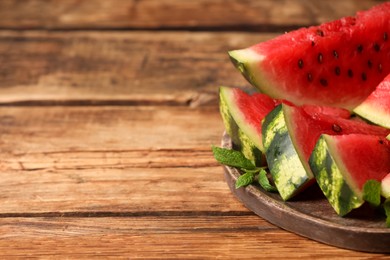 Photo of Slices of delicious ripe watermelon on wooden table, space for text