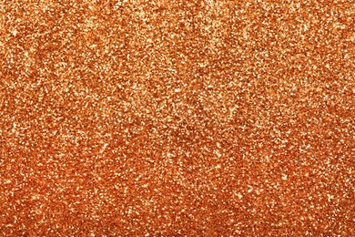 Beautiful shiny orange glitter as background, closeup